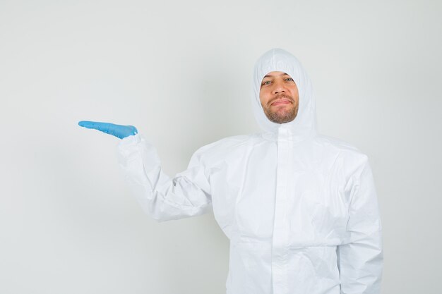 Male doctor holding palm as showing something in protective suit
