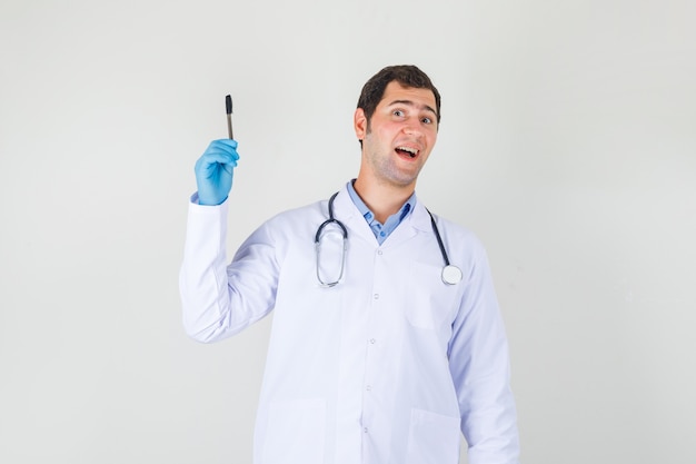 Male doctor holding pen in white coat, gloves and looking surprised