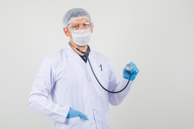 Male doctor holding stethoscope and looking at camera in protective clothes