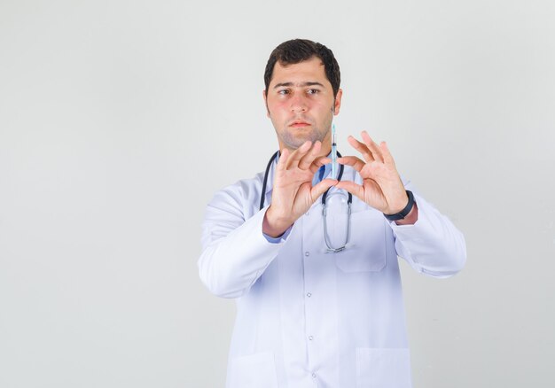 Male doctor holding syringe for injection in white coat front view.