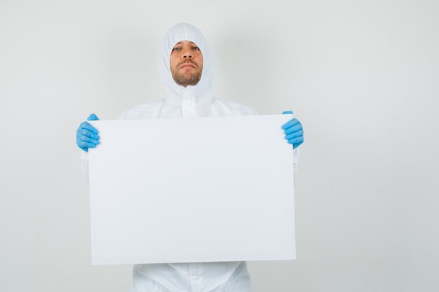 Male doctor holding white board in protective suit