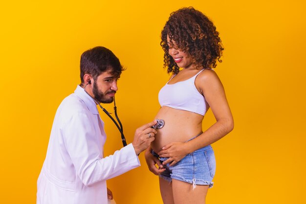 男性​医師​が​聴診器​で​妊婦​を​チェックしています​。​妊娠中​の​女性​の​世話​を​する​コンセプト