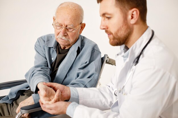 Male doctor and old man on a wheelchair isolated on a white background