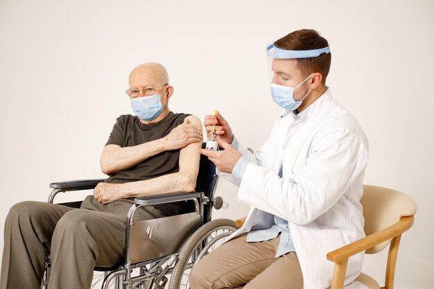 男性医師と白い背景で隔離の車椅子の老人