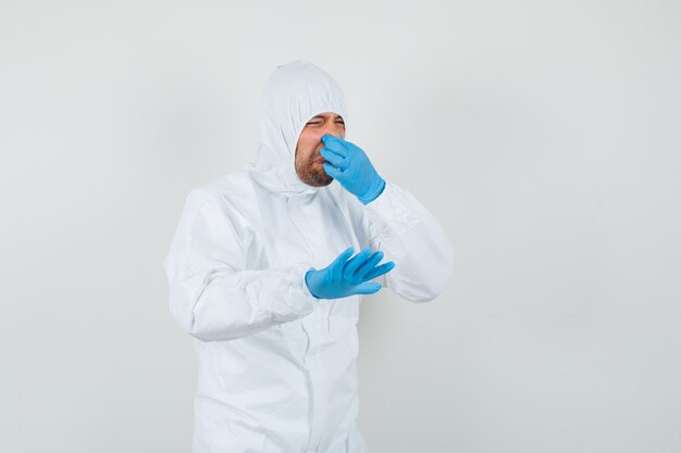 Male doctor pinching nose because of bad smell in protective suit
