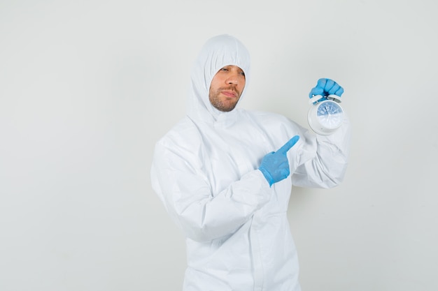 Male doctor pointing at alarm clock in protective suit