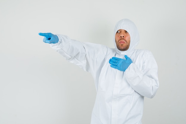 Male doctor pointing away, holding hand on chest in protective suit