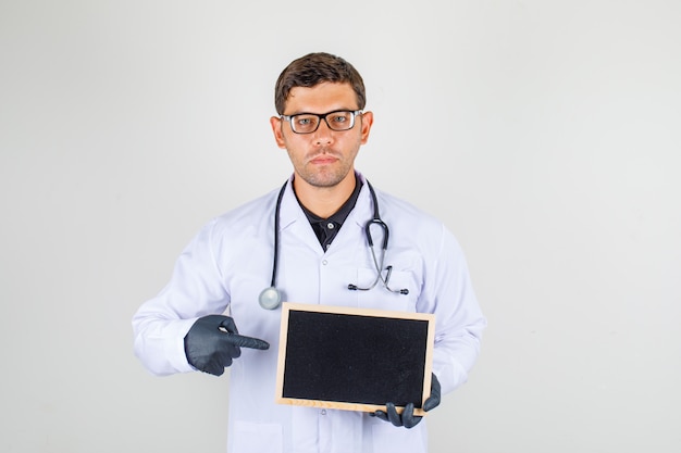 Male doctor pointing finger at blackboard in medical white robe