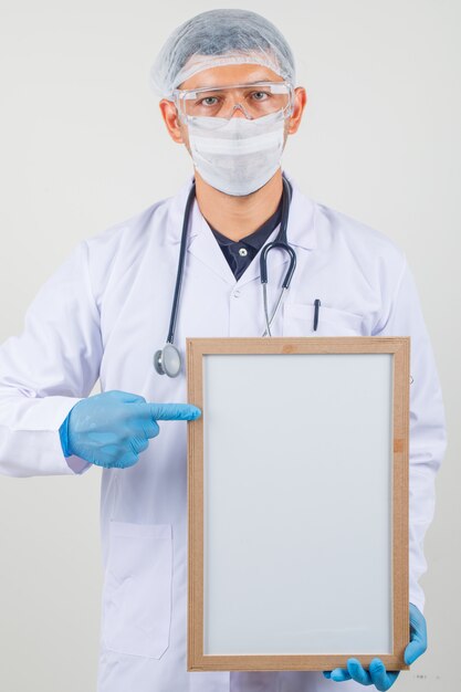 Мужской доктор, указывая пальцем на доску в защитной одежде