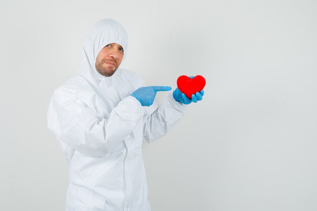 Male doctor pointing at red heart in protective suit