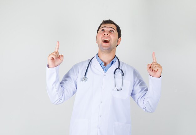 Male doctor pointing up fingers in white coat and looking happy