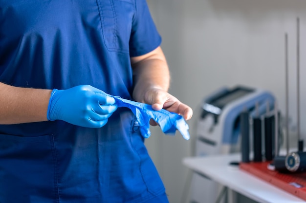 Free photo a male doctor puts on blue gloves before starting a procedure