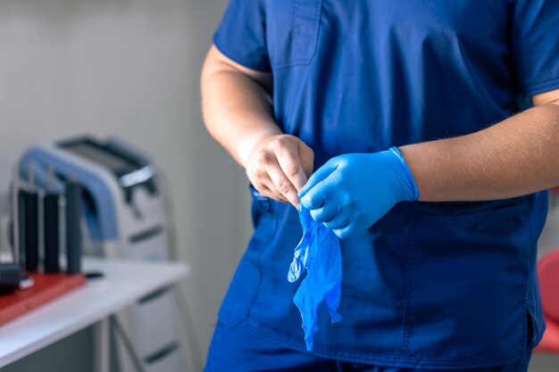 Foto gratuita un medico indossa guanti blu prima di iniziare una procedura