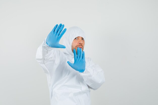Male doctor raising palms to defend himself in protective suit