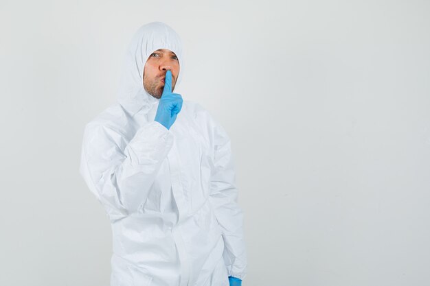 Male doctor showing silence gesture in protective suit