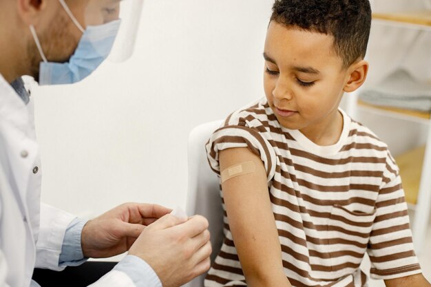 Male doctor stick a bandaid to a boy after a vaccination