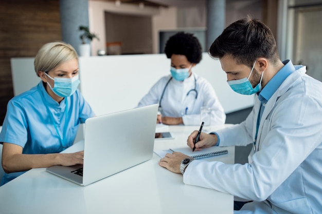 Мужчина-врач делает заметки во время работы с коллегами в медицинской клинике
