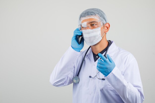 Male doctor talking on mobile phone in protective clothes