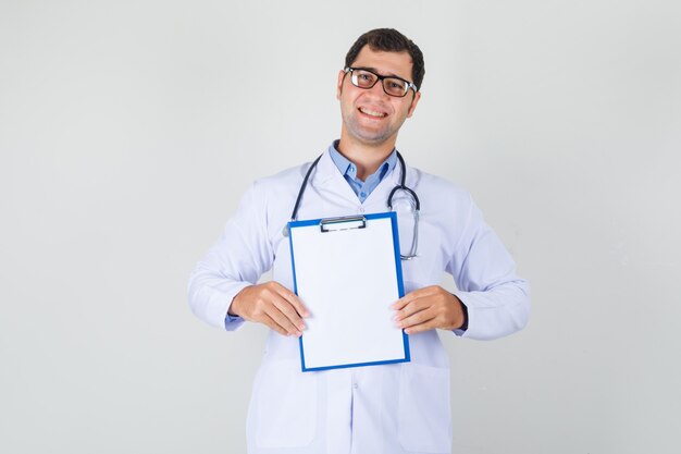 Male doctor in white coat, glasses holding clipboard and looking cheerful