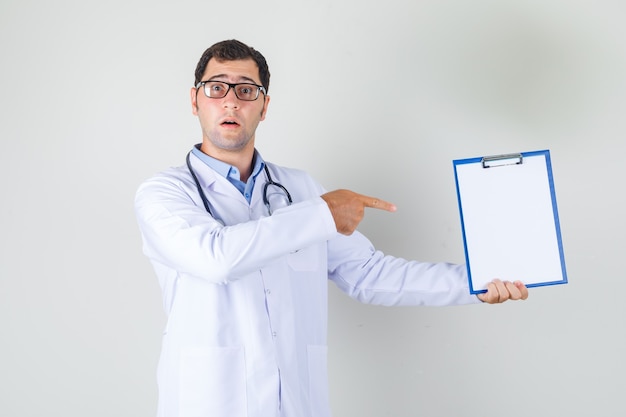 Male doctor in white coat, glasses pointing finger at clipboard