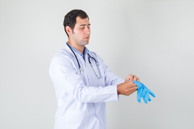 青い医療用手袋を着用し、注意深く見ている白衣の男性医師