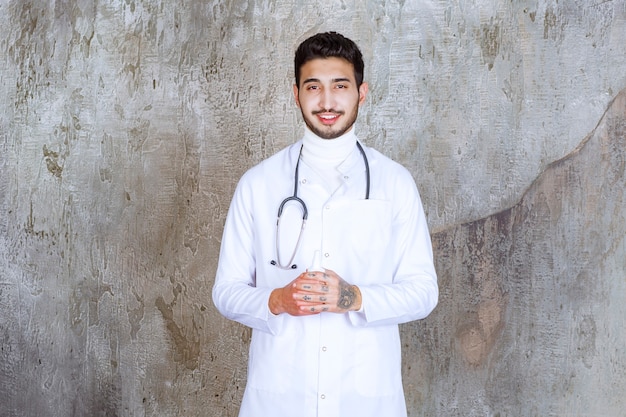 Male doctor with stethoscope holding a white hand sanitizer bottle.