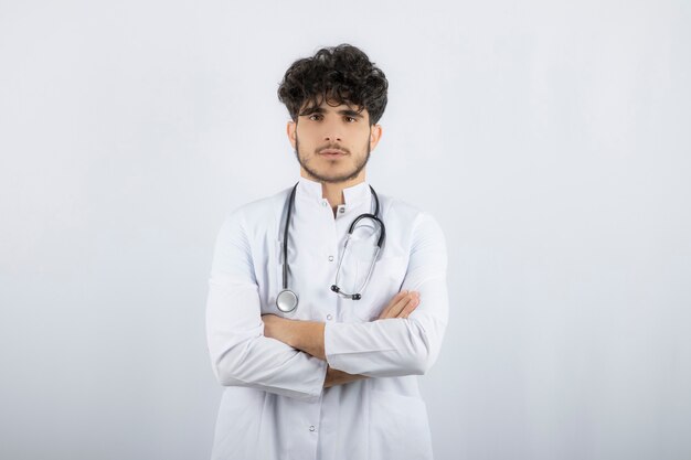 Foto gratuita medico maschio con uno stetoscopio in piedi e guardando la fotocamera.