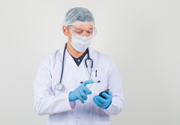 Male doctor working on smartphone in protective clothes