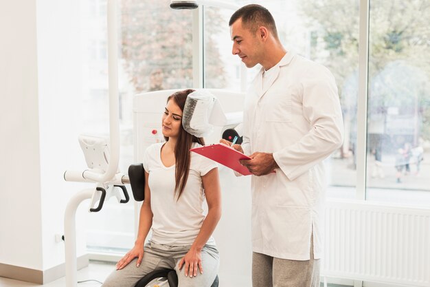 Male doctor writing patient condition on clipboard