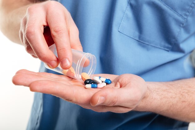 Мужчины-врачи разливают таблетки из бутылки на ладонь