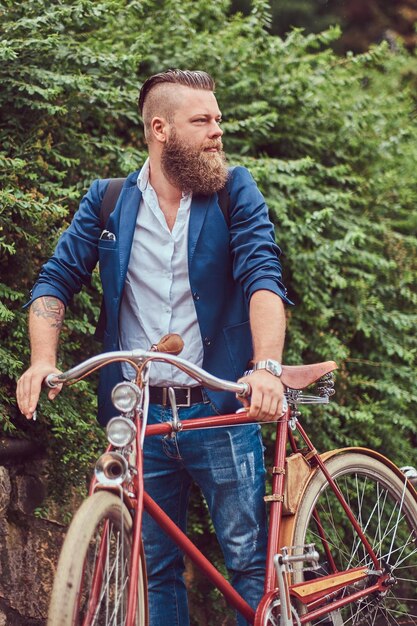 カジュアルな服を着て、都市公園でレトロな自転車で立っている男性。