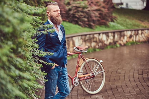 Free photo male dressed in casual clothes, standing with a retro bicycle in a city park.