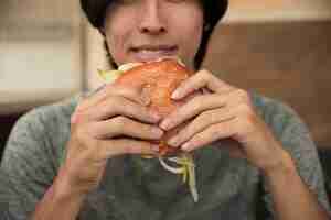 Free photo male eating hamburger in cafe