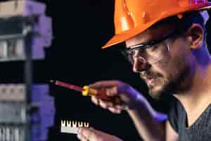 Free photo a male electrician works in a switchboard with an electrical connecting cable