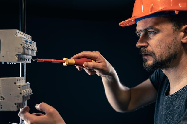 Foto gratuita un elettricista maschio lavora in un quadro elettrico con un cavo di collegamento elettrico