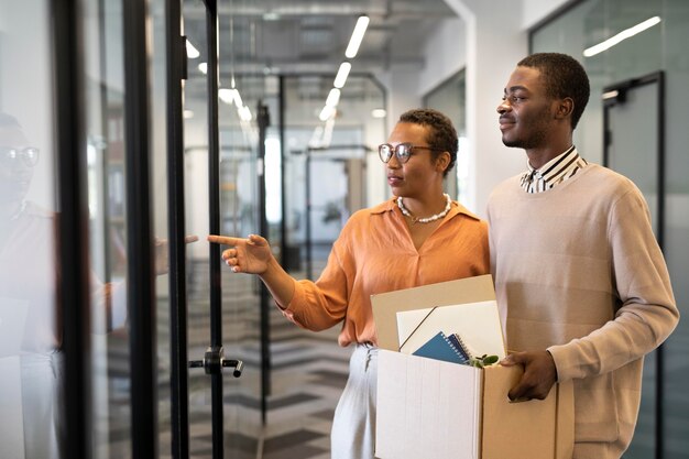 Male employee exploring his new new office job location while carrying box of belongings