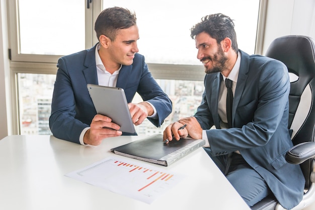 Male employee showing to his partner on digital tablet in the meeting