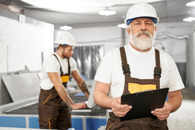 Male engineer in uniform and helmet keeping folder