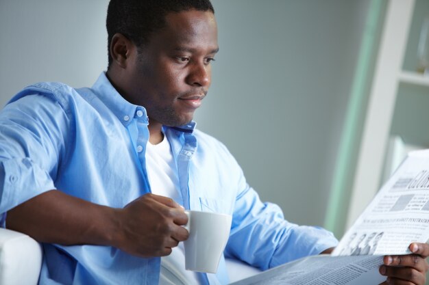 Male executive drinking coffee and reading the newspaper