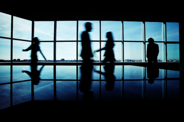 Free photo male executive staring through the window with businesspeople rushing