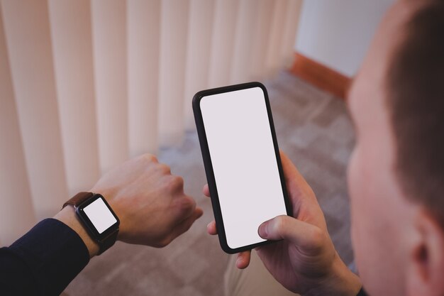 Male executive using mobile phone and checking time on wristwatch