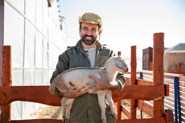 Foto gratuita agricoltore maschio che tiene una delle sue capre alla fattoria