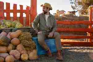 Foto gratuita agricoltore maschio che tiene il raccolto della zucca all'azienda agricola