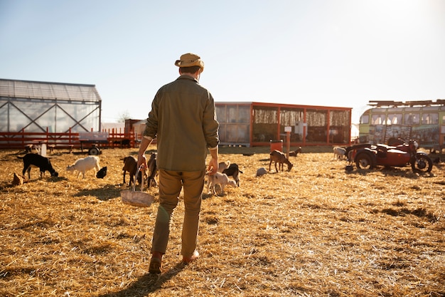 Agricoltore maschio che supervisiona i suoi animali nella fattoria