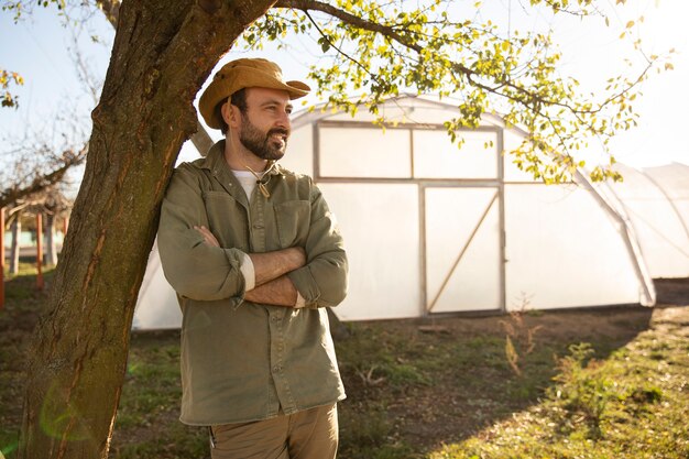 male farmer posing next to his greenhouse at the farm