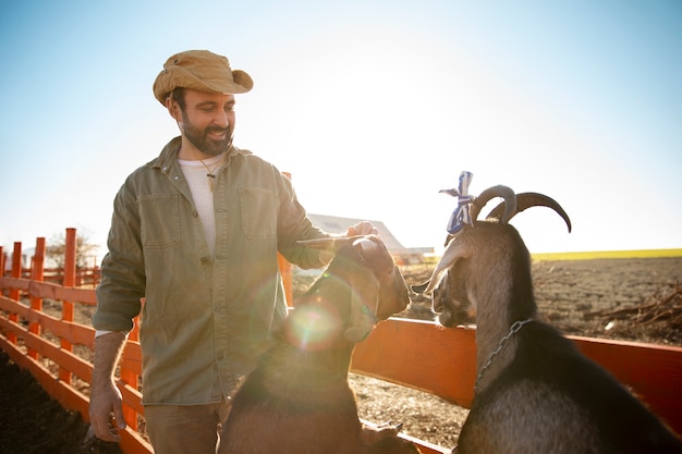 무료 사진 농장에서 염소를 돌보는 남성 농부