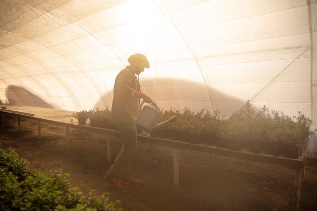 彼の農場で植物作物に水をまく男性の農夫