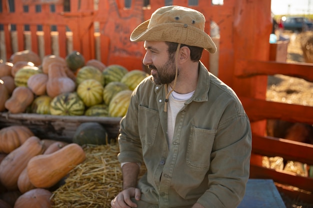 Free photo male farmer with the harvest of pumpkins and watermelons at his farm