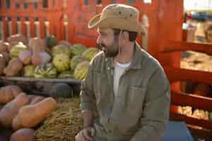 Free photo male farmer with the harvest of pumpkins and watermelons at his farm