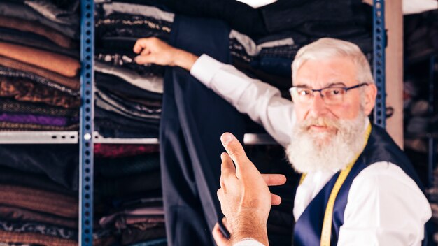 Male fashion designer taking fabric from shelf for his customer